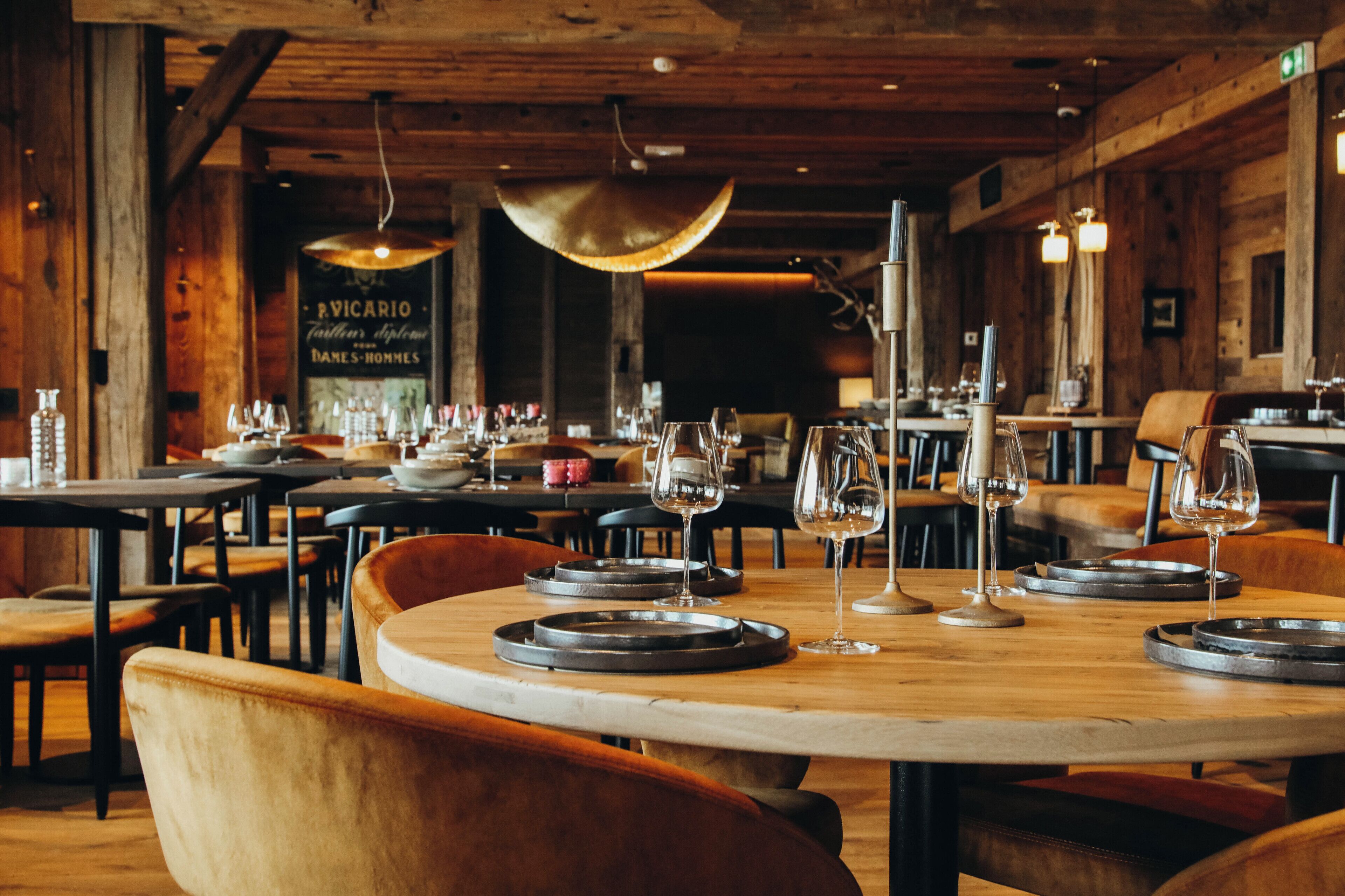 A restaurant with wooden interiors, round tables, and chairs.