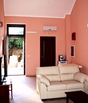 A living room with a sofa, a coffee machine, and a door leading to an outdoor area. - Monteciminiello (Francavilla Fontana)