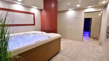 A modern spa room with a hot tub, wooden paneling, and a red-tiled accent wall.