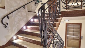 A modern interior with a spiral staircase, a large decorative wall, and a metallic elevator. - Grand Podhale Resort & Spa (Zakopane)
