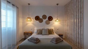 A modern bedroom with a large bed, bedside tables, and decorative wall art. - Monte Vale Organic Farm (Castro Verde)