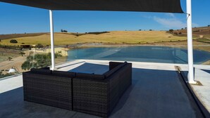 A covered outdoor seating area with a view of a pool and hills. - Monte Vale Organic Farm (Castro Verde)