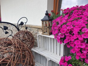 Wicker stoelen, een lantaarn en een plantenbak met roze bloemen.