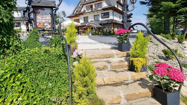 Een hotelingang met stenen trappen, een restaurant genaamd 'Restaurantez', en een bordje voor 'Bufet Sniadania 8:00-10:00'.