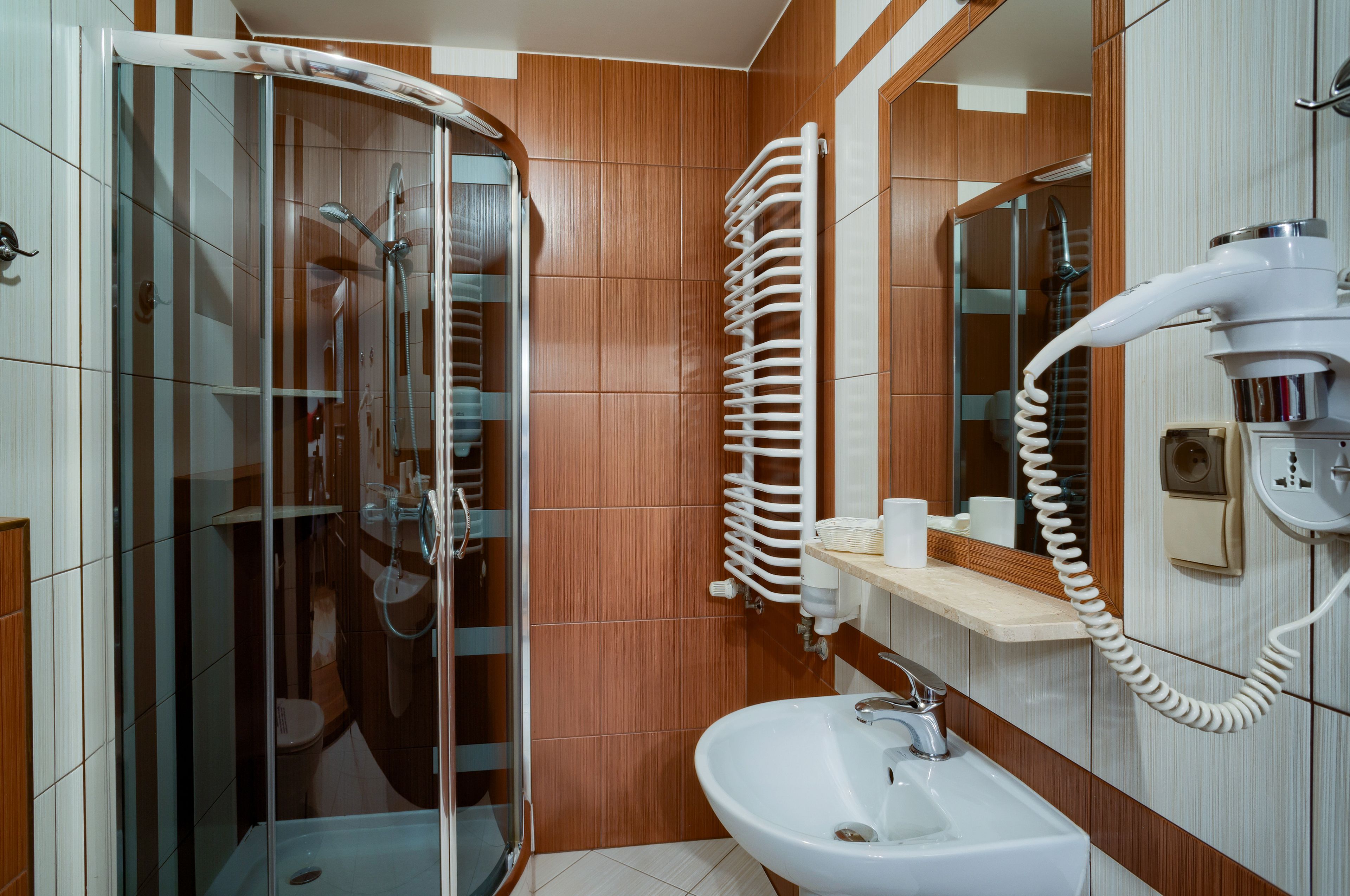 A bathroom with a glass-enclosed shower, a white sink, and a towel rack.