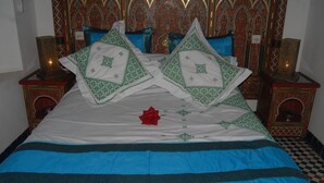 A bed with a blue and white bedspread, two decorative pillows, and a red rose. - Dar La Bague De Kenza (Fes)