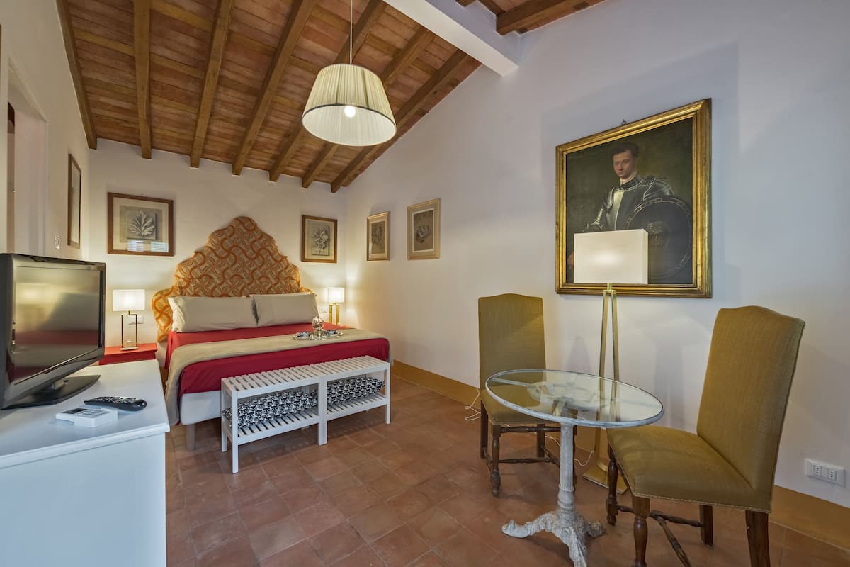 A hotel room with a bed, a television, a glass table, and a chair.