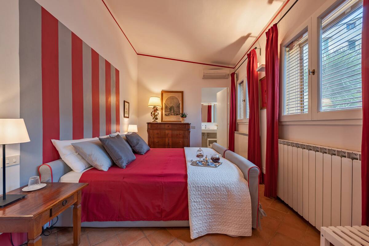 A bedroom with a bed, bedside tables, a dresser, a mirror, and a window with curtains.