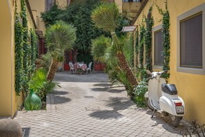 A narrow cobblestone street with a parked white scooter and a table with chairs in the background. - Drom Florence Rooms & Apartments (Florence)
