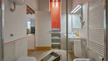 A modern bathroom with a glass shower enclosure, a white bathtub, and a separate sink area.