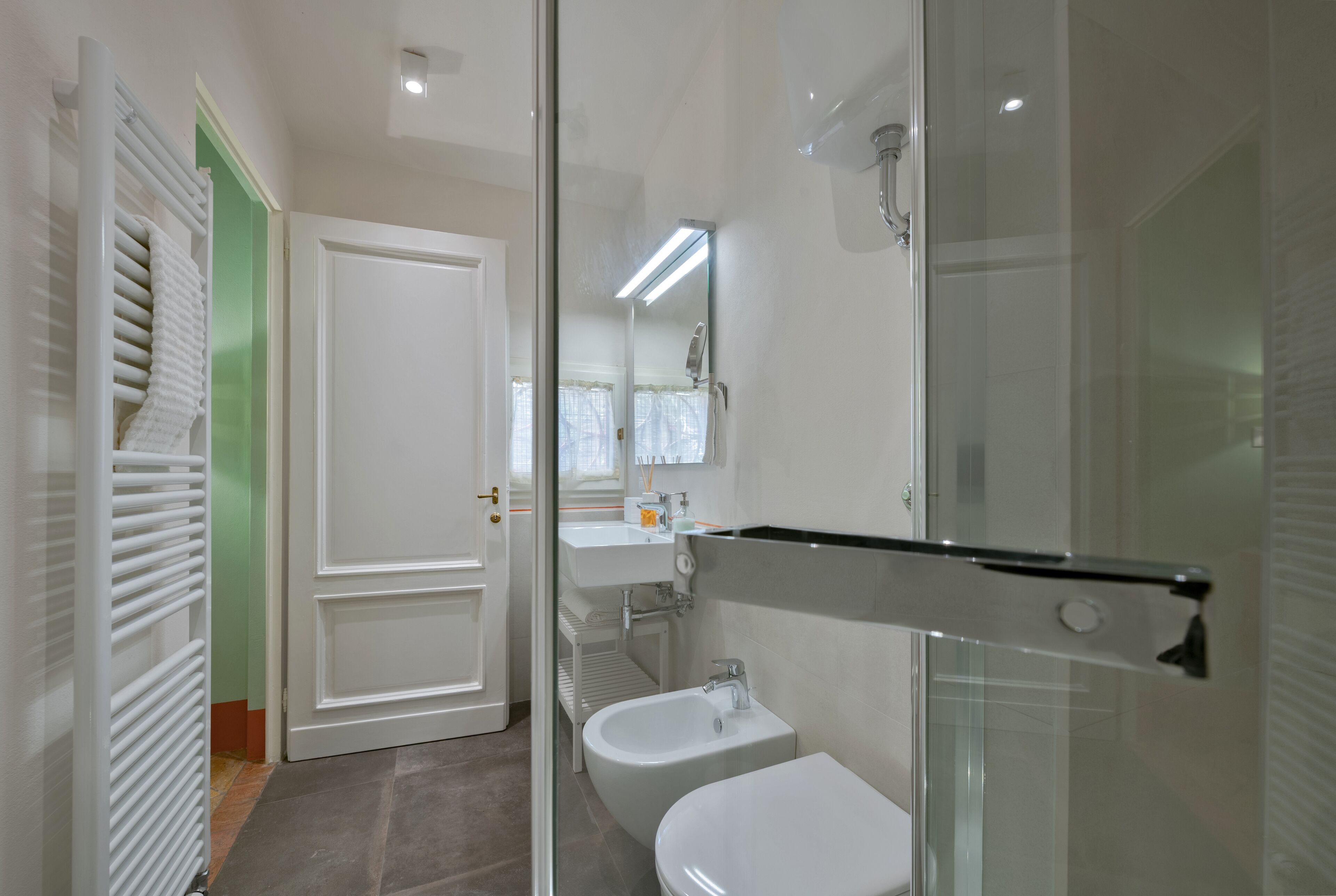 Ein modernes Badezimmer mit Duschkabine aus Glas, einem weißen Waschbecken und einer Toilette.