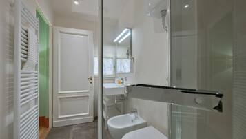 Ein modernes Badezimmer mit Duschkabine aus Glas, einem weißen Waschbecken und einer Toilette.