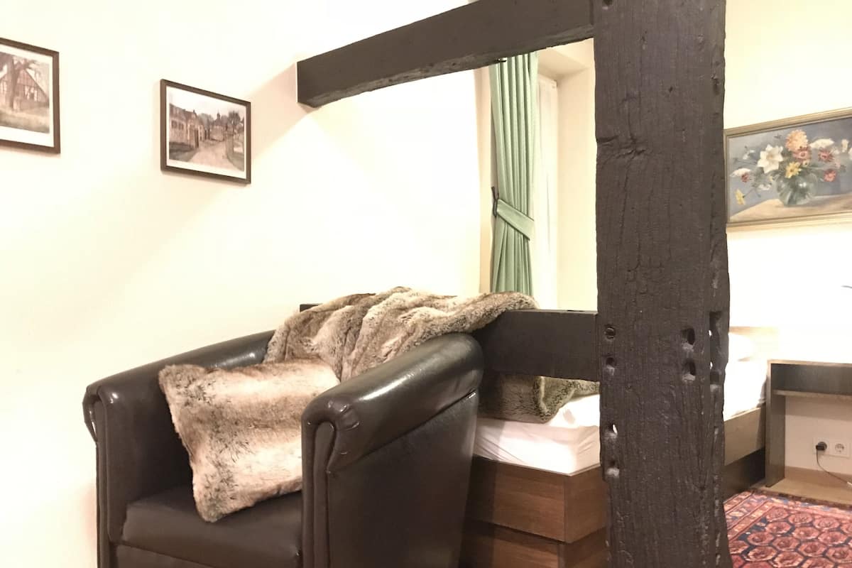 Een gezellige kamer met een leren fauteuil, een houten bedframe en een klein nachtkastje.
