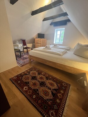 A bedroom with a loft bed, a wooden dresser, a chair, a small table, and a patterned rug. - Altes Gasthaus Nagel (Oerlinghausen)