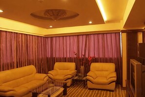A living room with a sofa, armchairs, a coffee table, and a television. - Linhai International Hotel (Funing)