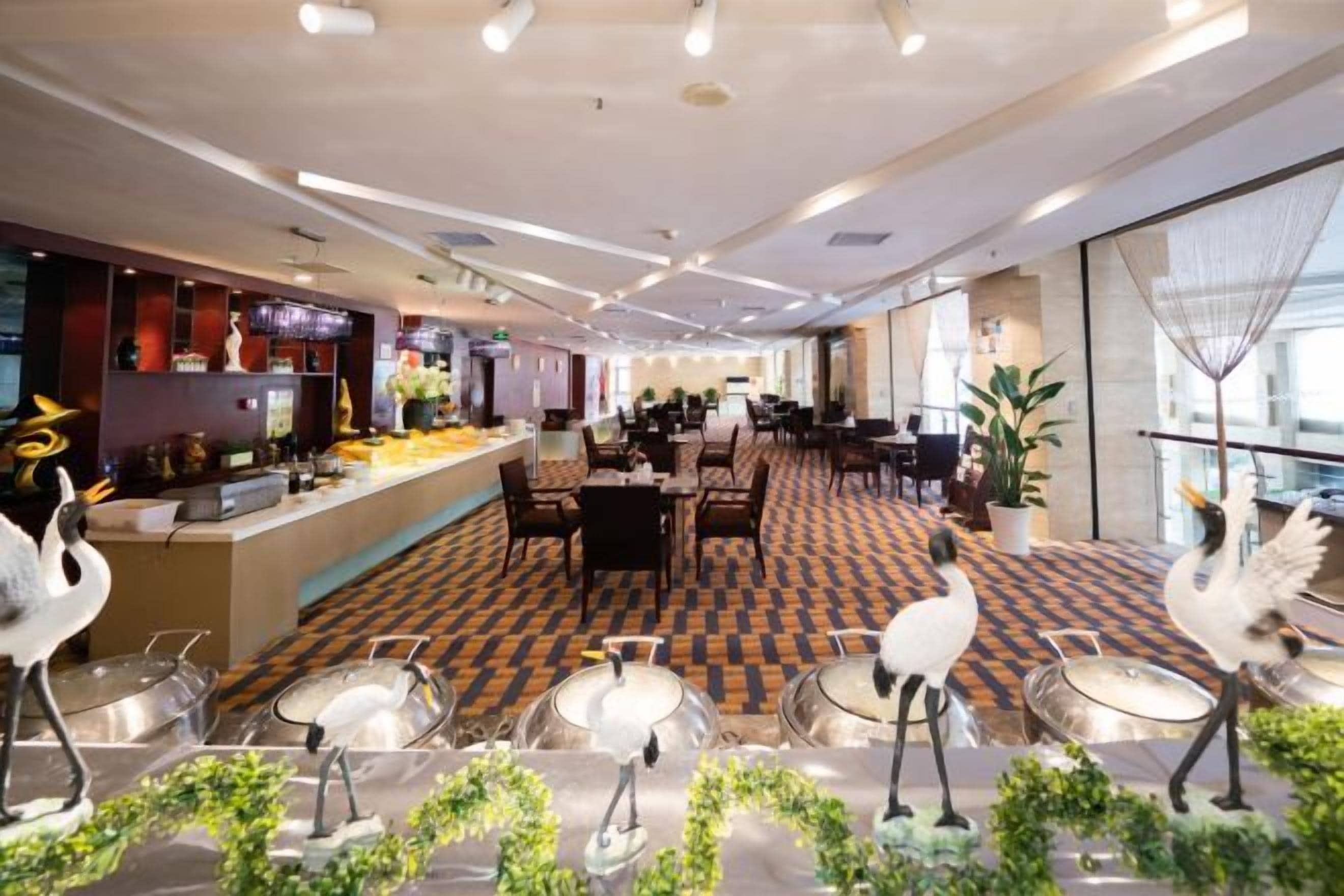 A spacious hotel lobby with a check-in counter, dining area, and seating arrangements.