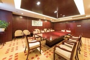 A conference room with a long table and chairs, a potted plant, and a wall with calligraphy. - Linhai International Hotel (Funing)