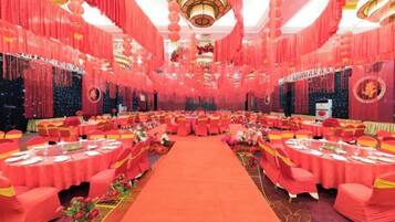 A banquet hall with round tables, red drapery, and a central aisle.