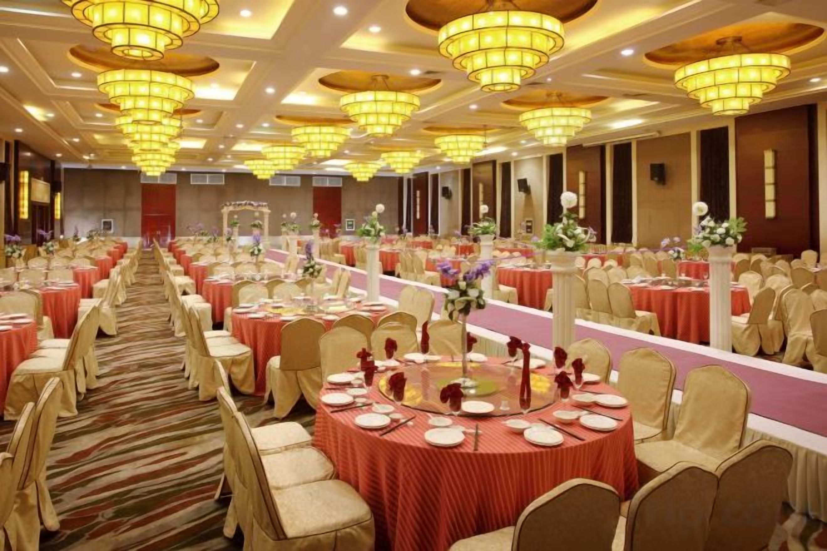 A banquet hall with round tables, chairs, and chandeliers.