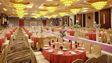 A banquet hall with round tables, chairs, and chandeliers.