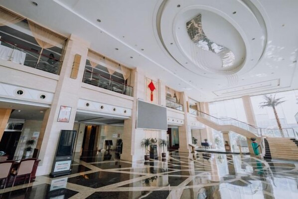 A spacious lobby with a high ceiling, a central atrium, and a staircase leading to upper levels. - Linhai International Hotel (Funing)