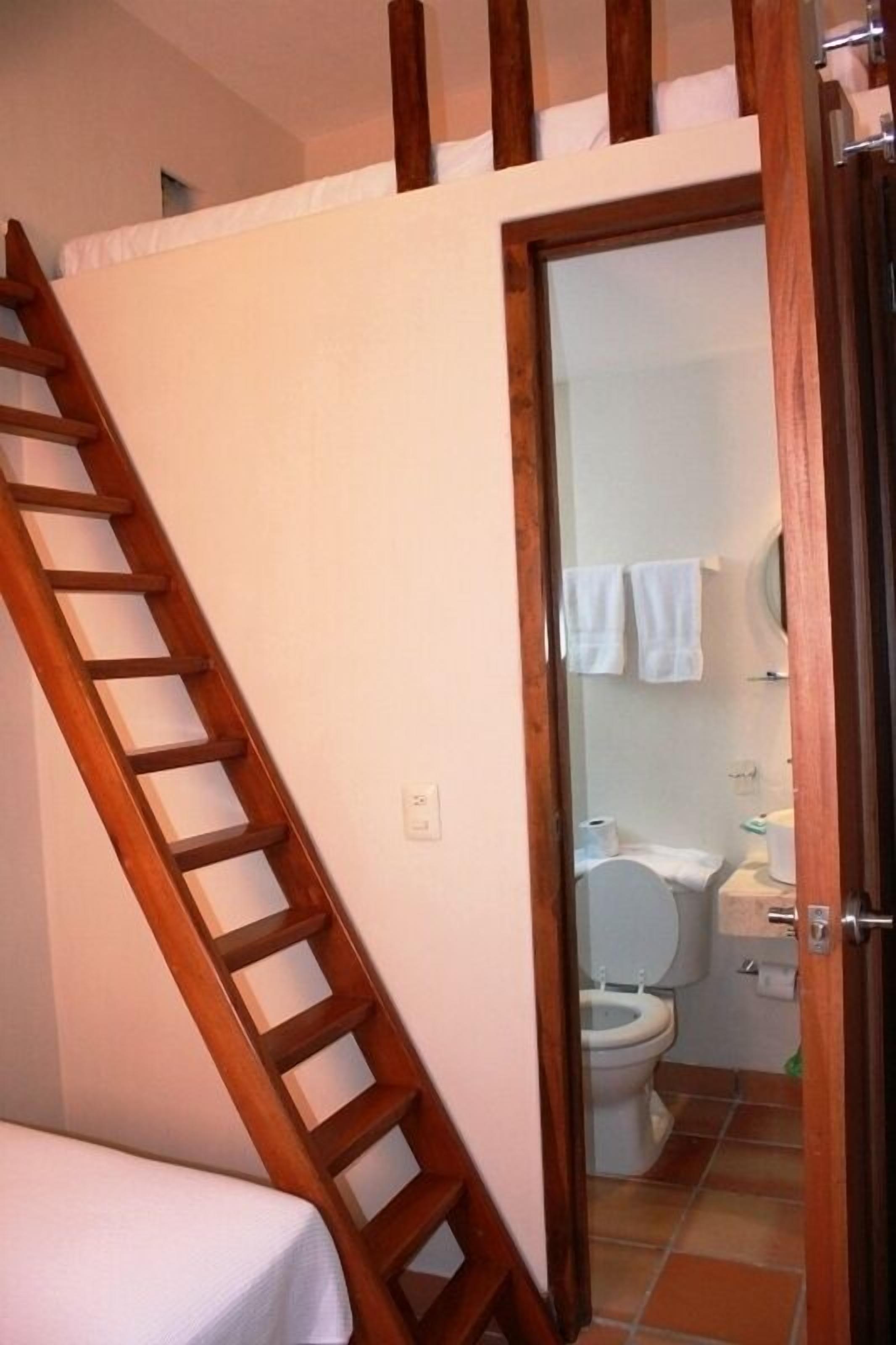 A bedroom with a wooden ladder leading to a lofted sleeping area.