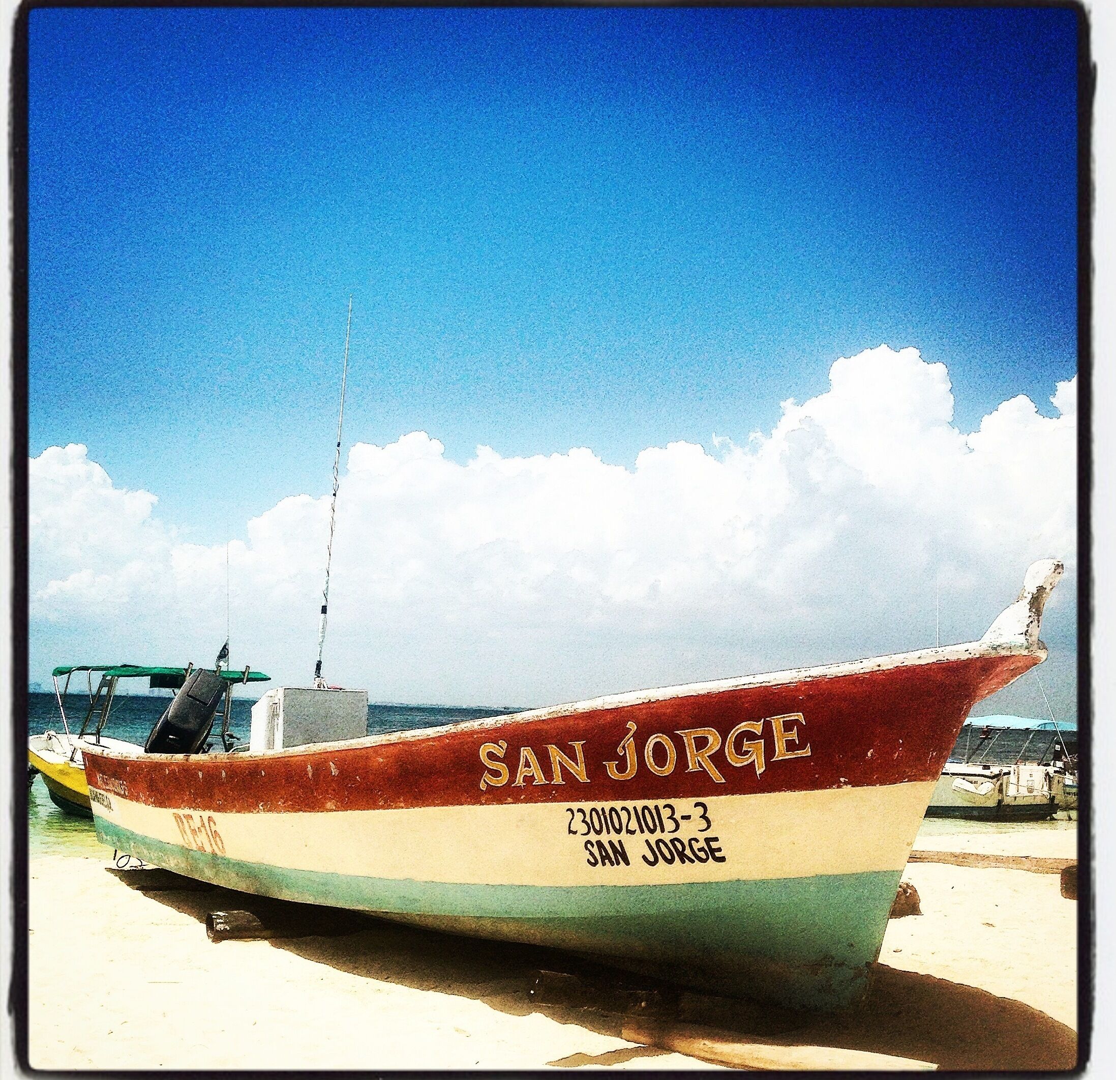 A boat named 'SAN JORGE' with the registration number '230102013-3' on a sandy beach.