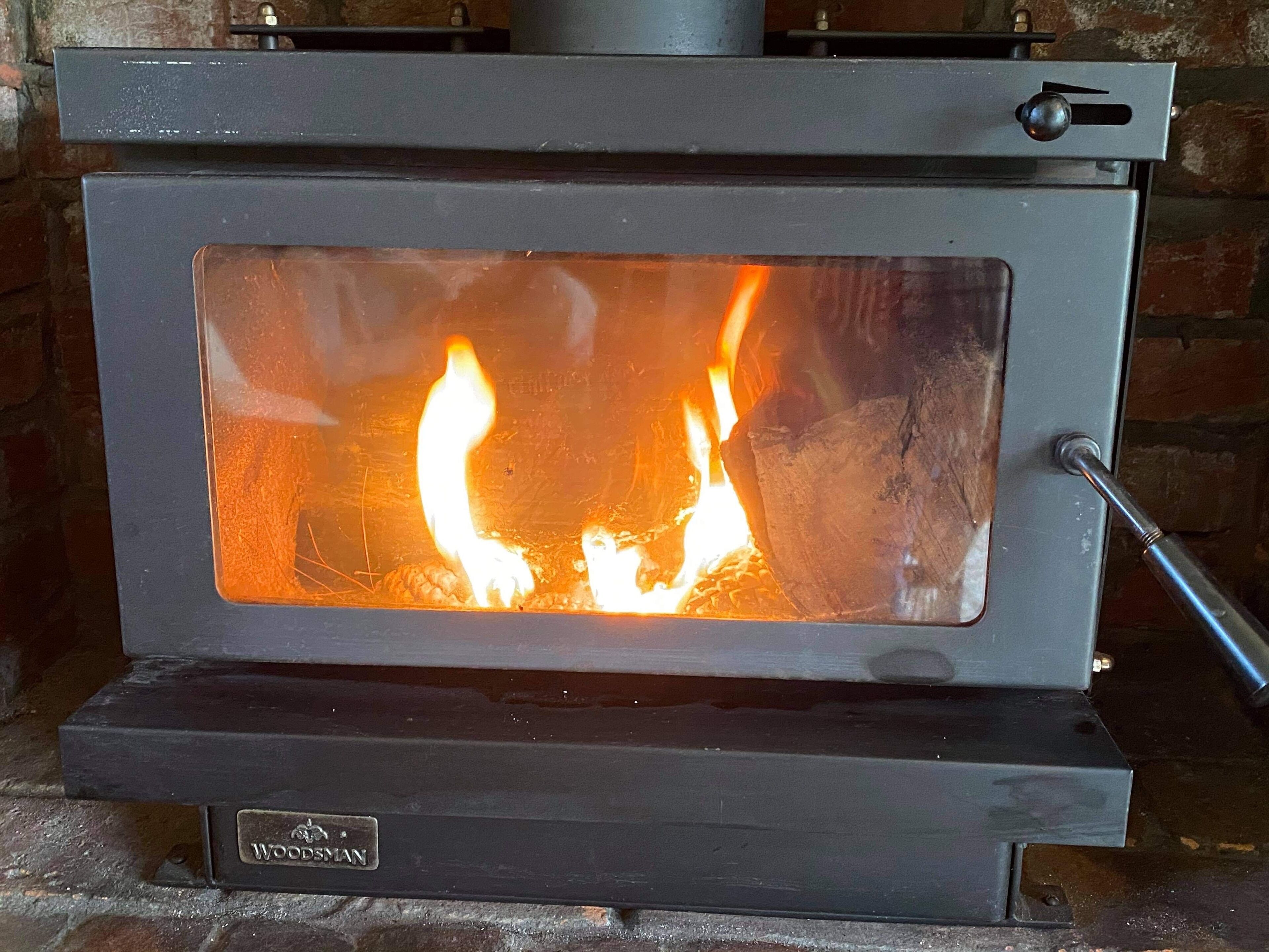 Un foc de llenya amb porta de vidre, un comandament i un mànec metàl·lic.