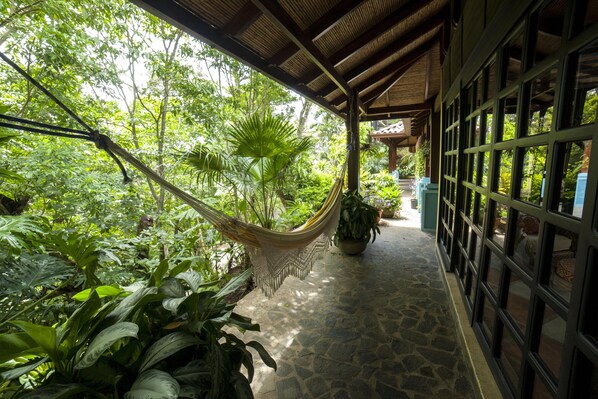 A covered walkway with a hammock, potted plants, and a stone floor. - Cool Bali Style Villa, w/stunning views, HiSpeedWifi., 3Brs. solar heated pool. (Atenas)