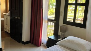 A hotel room with a bed, a desk, a wardrobe, and a window with a view of palm trees. - Experience the jungle of Costa Rica!! Direct oceanfront property for 8 guests. (Puntarenas)