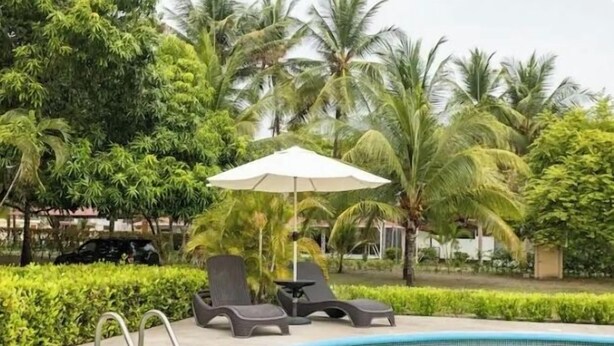 A pool area with lounge chairs and an umbrella, surrounded by lush greenery and palm trees. - Experience the jungle of Costa Rica!! Direct oceanfront property for 8 guests. (Puntarenas)