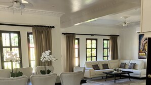 A spacious living room with a white sofa, a dining table with chairs, and a ceiling fan. - Experience the jungle of Costa Rica!! Direct oceanfront property for 8 guests. (Puntarenas)