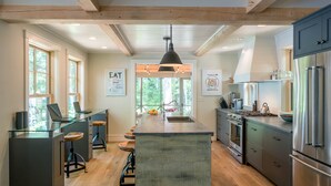 A modern kitchen with a central island, bar stools, a stove, and a refrigerator. - Lakeside life at its best! (Enfield)