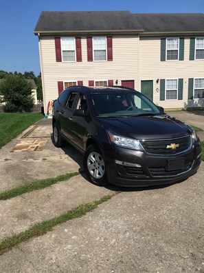 Un Chevrolet SUV negro estacionado frente a una casa de dos pisos con garaje.