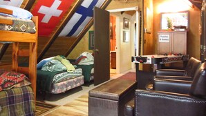 A cozy attic room with a bed, a couch, and a small table. There are flags hanging on the wall, and a cabinet labeled "Puzzles & Games". - Year-Round Lake Tahoe Getaway -- Comfortable and Spacious! (South Lake Tahoe)
