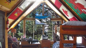 A cozy attic room with a sloped ceiling, a bed, a desk, and a window overlooking trees. - Year-Round Lake Tahoe Getaway -- Comfortable and Spacious! (South Lake Tahoe)