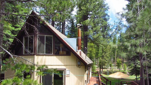 A two-story cabin with a deck, surrounded by trees. - Year-Round Lake Tahoe Getaway -- Comfortable and Spacious! (South Lake Tahoe)