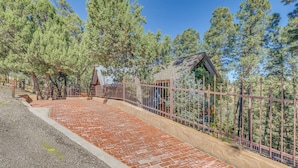 A paved walkway with a brick pattern leading to a fenced area with a small building. - 2 Mi to Village of Ruidoso! 'Little Pine Cottage' (Ruidoso)