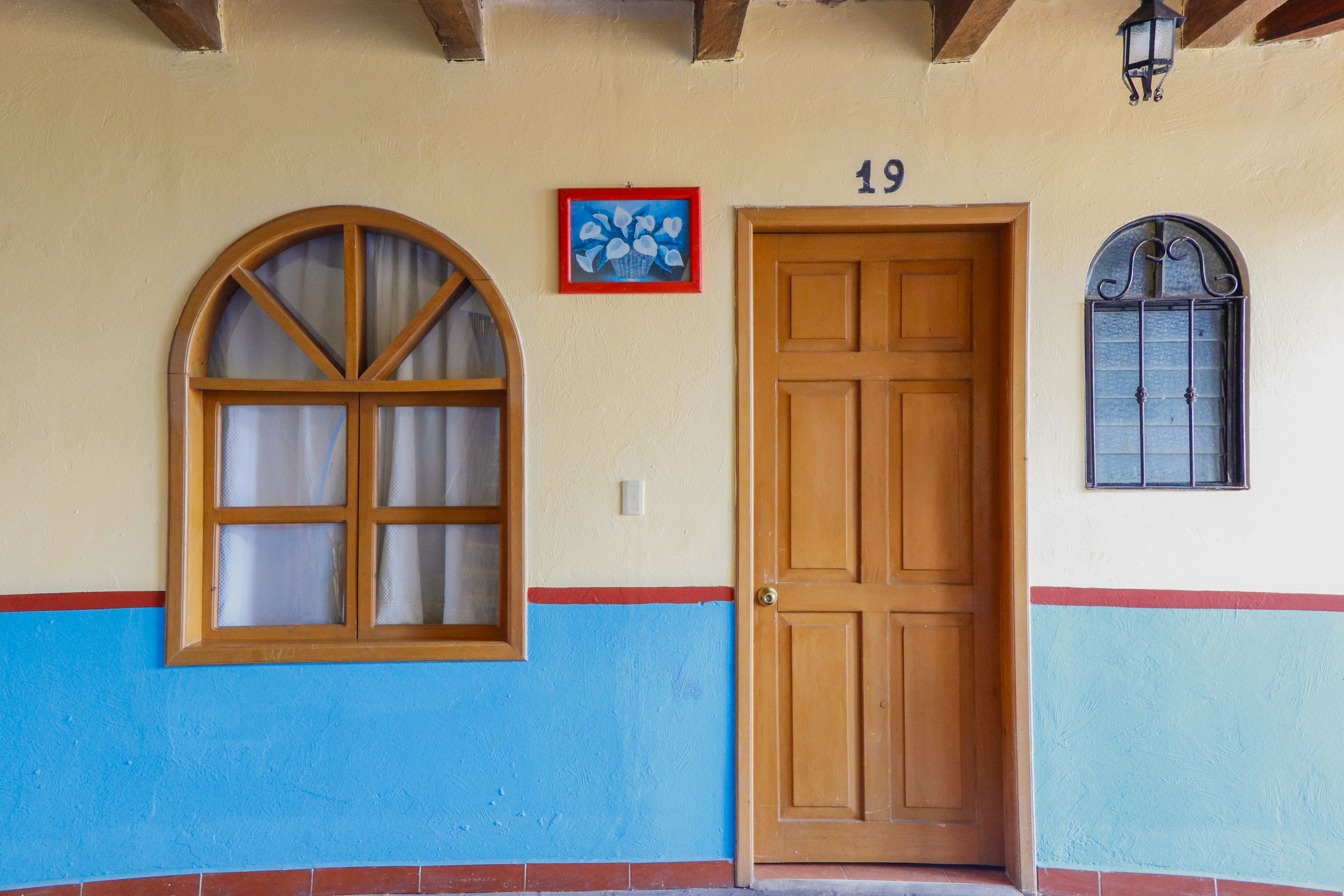 A building facade with a large arched window, a wooden door, and a small window with metal bars.