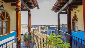 Ein Balkon mit Blick auf die Stadt, mit Fliesenboden und Holzsäulen.