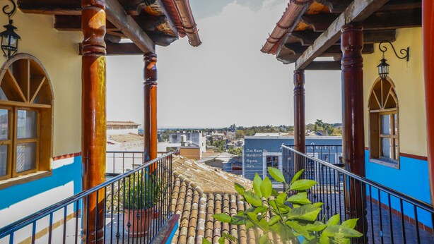 Ein Balkon mit Blick auf die Stadt, mit Fliesenboden und Holzsäulen.