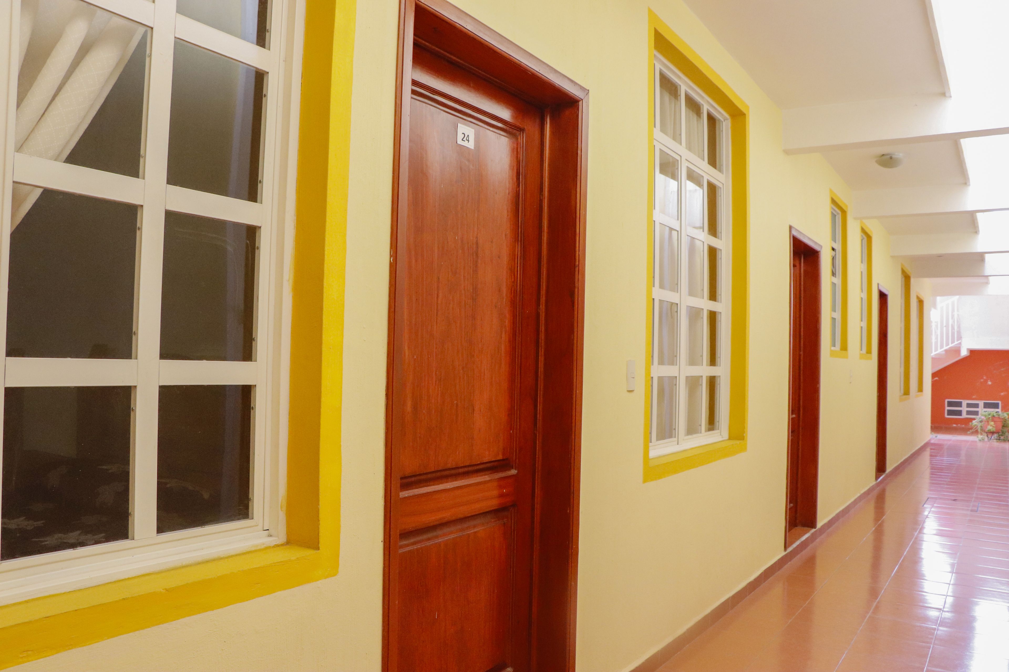 A corridor with doors and windows, a tiled floor, and a ceiling with a light fixture.