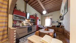 A cozy kitchen with wooden beams, a dining area with a table set for two, and a book open on a bench. - Apartment/ flat - Palaia (Palaia)
