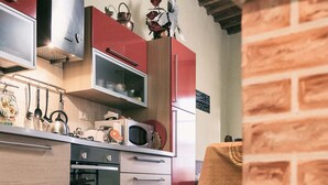 A kitchen with wooden cabinets, a microwave, and a stove. - Apartment/ flat - Palaia (Palaia)