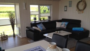 A modern living room with a black leather sofa, a white coffee table, and decorative items.