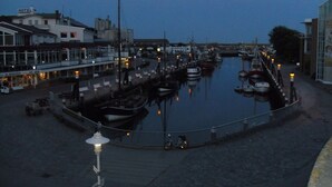 A marina with boats docked, a hotel on the left, and a pedestrian walkway.