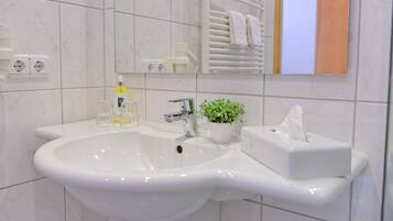 Un baño con lavamanos blanco, espejo y perchero.