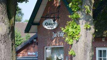 Ett hotellskylt med texten ”Hotel Zur Cidhe” och en traditionell fasad i tegel.