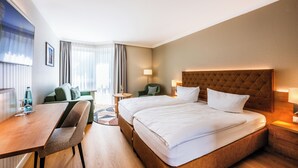 Una habitación de hotel con cama, escritorio, silla, sofá y una pequeña mesa.