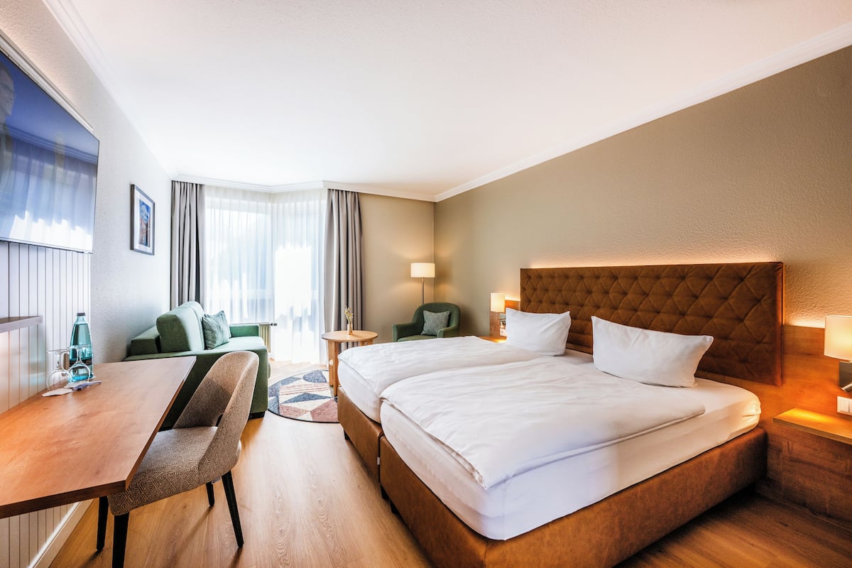 Una habitación de hotel con cama, escritorio, silla, sofá y una pequeña mesa.